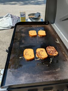Slices of French toast cooking on a Blackstone griddle
