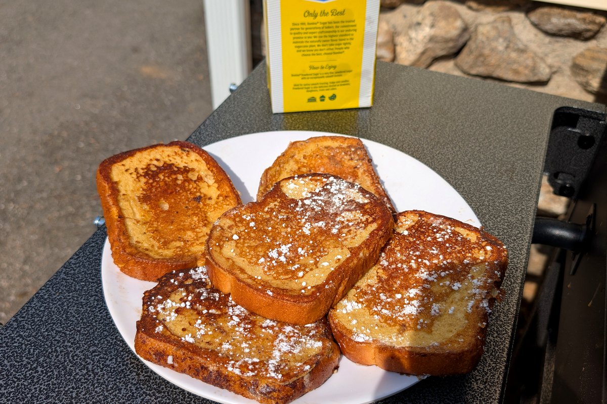 Blackstone French toast slices dusted with powdered sugar on a white plate